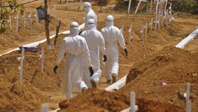 Health workers walk inside a new graveyard as they move burried people suspected of dying from the Ebola virus on the outskirts of Monrovia, Liberia, Wednesday, March 11, 2015. Liberians held a church service Wednesday for families who lost members to Ebola to mark the country’s 99th celebration National Decoration Day, a holiday normally set aside for people to clean up and re-decorate the graves of their lost relatives.
