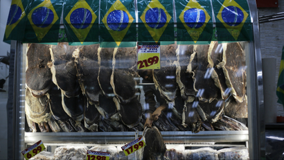 A vendor selling meat arranges his wares next to a display of Brazilian flags in Sao Paulo.