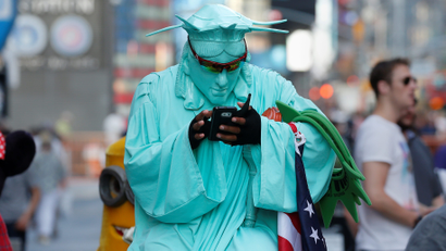 A person wearing a Statue of Liberty outfit to pose for tips checks his cell phone during warm weather in Times Square in the Manhattan borough of New York, New York, U.S., October 19, 2016.