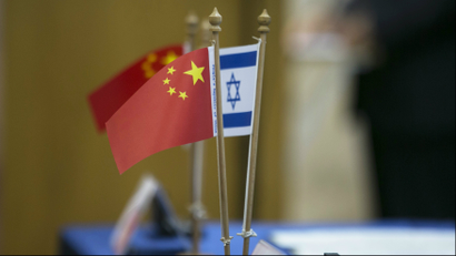Chinese and Israeli flags are seen on a table during a signing ceremony marking a launch by Tel Aviv University and Beijing's Tsinghua University of a $300 million joint centre for innovative research and education, in Tel Aviv May 20, 2014. China's purchase, announced on Thursday, of a controlling stake in Israel's largest food maker reflects a broader surge in Chinese investment in an economy largely tethered to Western markets.