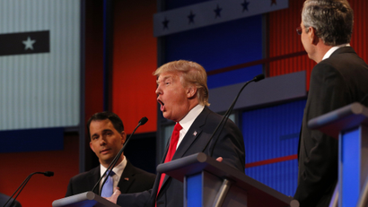 Donald Trump answers a question as fellow candidates Wisconsin Governor Scott Walker (L) and former Florida Governor Jeb Bush (R) listen at the first official Republican presidential candidates debate of the 2016 U.S. presidential campaign