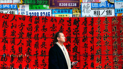 A man stands outside a closed shop covered with Chinese calligraphy on red papers to celebrate the upcoming Chinese New Year of the Goat in Hong Kong February 9, 2015.