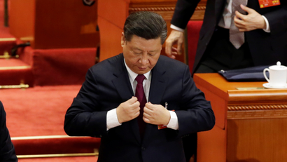 Chinese President Xi Jinping adjusts his attire at the end of the opening session of the National People's Congress (NPC) at the Great Hall of the People in Beijing, China March 5, 2018.
