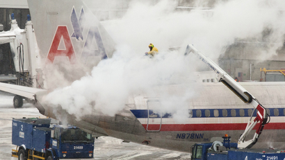 An American Airlines crew member sprays de-icing solution on a plane during a winter nor'easter snow storm in Boston, Massachusetts January 2, 2014