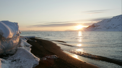 The sun shines low in the sky just after midnight over a frozen coastline near the Norwegian Arctic town of Longyearbyen, April 26, 2007. The sea water is normally frozen solid at this time of year but global warming may be warming the region. REUTERS/Francois Lenoir