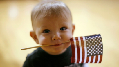 Dylan Curry, 11 months old, carries a U.S. flag in his mouth as he waits for his U.S. Army soldier father to return from Iraq before a ceremony at Fort Carson in Colorado Springs, Colorado February 12, 2009. About 280 soldiers from the 3rd Brigade Combat Team, 4th Infantry Division returned following their 15-month deployment to Iraq.