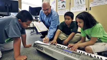 Music teacher teaching kids how to play the electric piano.