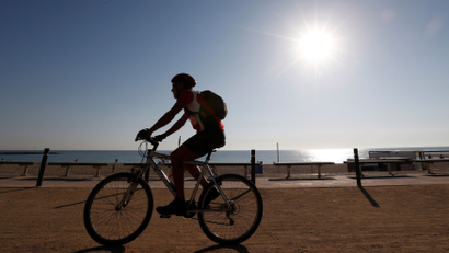 A man rides his bicycle on a hot day in Barceloneta beach in Barcelona
