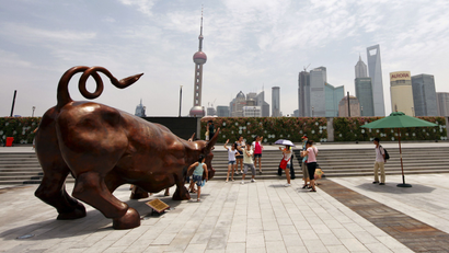 People pose next to the Charging Bull statue by Italian-American artist Arturo Di Modica, at the financial square on the Bund in Shanghai July 8, 2010. REUTERS/Aly Song