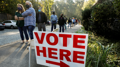 Voters wait in line by a "vote here" sign