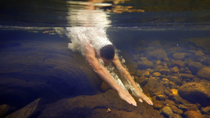 Russell Norris, 15, of Tylertown, Miss., dives into the chilly Swift River at Coos Canyon in Byron, Maine.