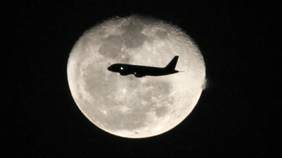 A passenger jet flies in front of the moon in Bogota