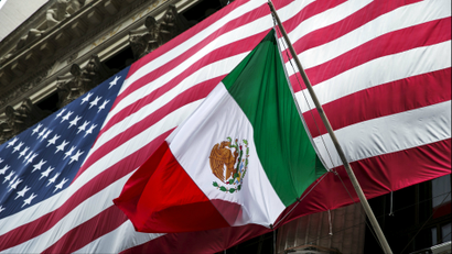 The flag of Mexico in front of a large U.S. flag in front of the New York Stock Exchange