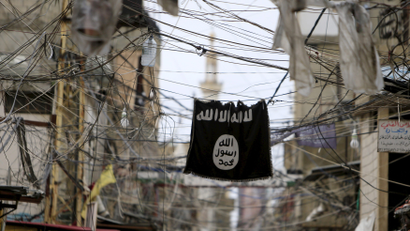 An Islamic State flag hangs amid electric wires over a street