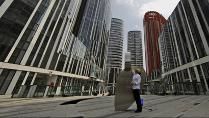 A Chinese woman cleans a banner outside commercial and residential buildings in Beijing, China, Tuesday, May 18, 2010. Chinese Premier Wen Jiaobao commented Friday, that Beijing will act "decisively" to cool surging housing prices. (AP Photo/Muhammed Muheisen)