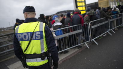 A police officer keeps guard as migrants arrive at Hyllie station outside Malmo.