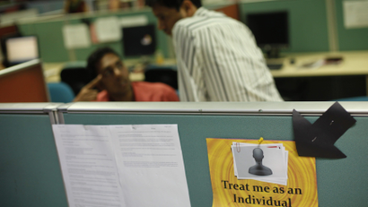 Employees work behind sign on floor of outsourcing company WNS in Mumbai