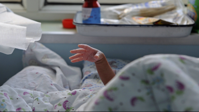 A baby stretches its hand from under a quilt at a local hospital in Jiaxing