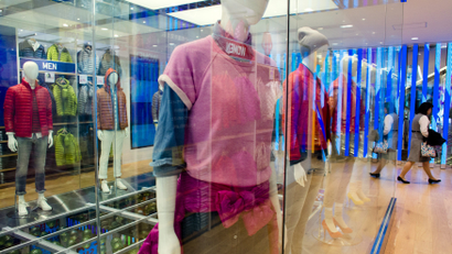 A woman walks past mannequins in brightly colored clothes