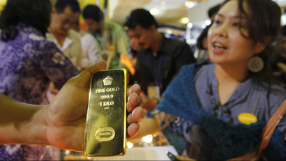 A man shows a gold bar to customers at a Jewellery Expo in Jakarta.