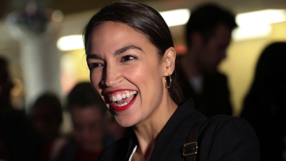 AOC smiling as she greets someone.