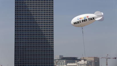 A blimp reading "Google must pay tax" is seen floating over the Tel Aviv skyline