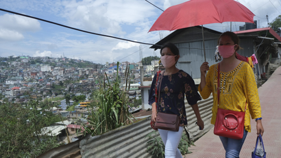 Naga girls wearing face masks walk on a street in Kohima,