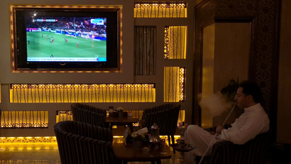 A Saudi man smokes shisha while watching a broadcast of Bundesliga highlights, pirated by beoutQ, at a local cafe in Khobar