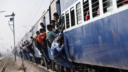 Passengers travel in an overcrowded train near a railway station at Loni town