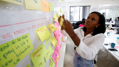 A woman attaches sticky notes to a whiteboard.