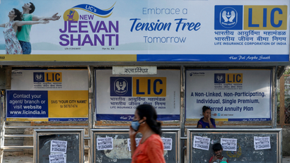 A woman walks past a bus stop with Life Insurance Corporation of India (LIC) advertisement in Mumbai