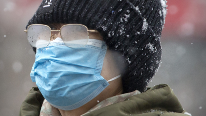 A woman's eyeglasses are fogged up as she wears a face mask during a snowfall in Beijing, Sunday, Feb. 2, 2020.