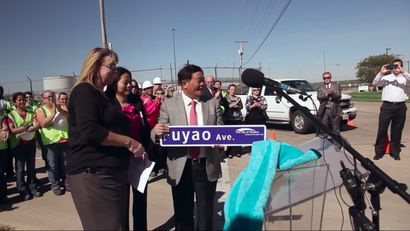 Cao Dewang, founder of Fuyao, accepts a road sign named after Fuyao glass in the US.