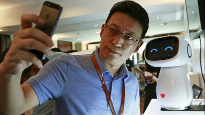 A visitor takes a selfie with Baidu's robot Xiaodu at the 2015 Baidu World Conference in Beijing, China, September 8, 2015. Xiaodu, an artificial intelligent robot developed by Baidu, has access to the company's search engine database and can respond to voice commands