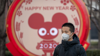 A man wears a face mask as he walks past a display for the upcoming Lunar New Year, the Year of the Rat, in Beijing, Wednesday, Jan. 22, 2020.