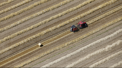 An aerial view shows a French farmer in his tractor making bales of straw after wheat harvest in his field.