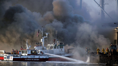 Los Angeles firefighters watch as smoke from a dock fire continues to rise at the Port of Los Angeles in the Wilmington section of Los Angeles on Tuesday, Sept 23, 2014. The fire that forced evacuations from the wharf continues to smolder but officials say it's under control. Nearly 12 hours after starting, the blaze is sending up huge plumes of smoke that is drifting over Los Angeles Harbor early Tuesday.