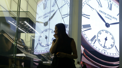 A woman looks at watches displayed at the exhibition stand of Swiss watch manufacturer Patek Philippe at Baselworld fair.