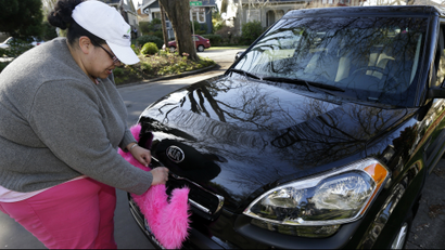 Lyft Driver adjusting the pink mustache on her car.