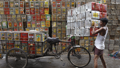 A man loads empty containers of edible oil onto a tricycle at a roadside in Kolkata