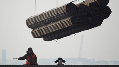 Port workers watch as steel pipes are loaded onto a freighter ship at Cao Feidian Port in Tangshan, in northern China's Hebei province, Monday, Feb. 20, 2012. (AP Photo/Alexander F. Yuan