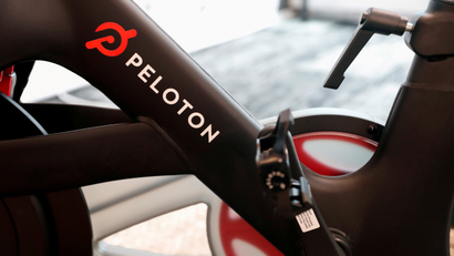 A close-up of a Peloton exercise bike with the company's logo.