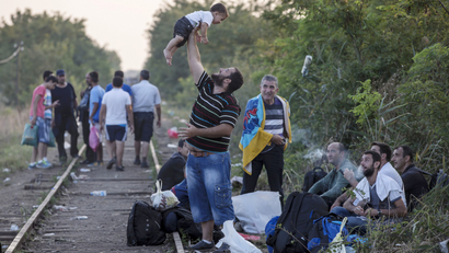 A migrant, hoping to cross into Hungary, plays with a childA migrant, hoping to cross into Hungary, plays with a child.
