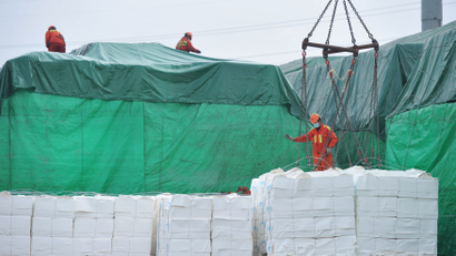 Workers wearing face masks unload imported paper pulp from a cargo ship at a port in Qingdao, Shandong province, China February 11, 2020.