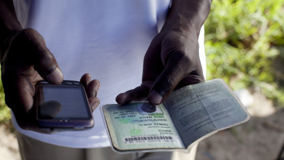 An employee of a bank checks a South African ID document via mobile phone as he sells accounts on the street in 2011 in Khayelitsha, the poorest and largest township outside Cape Town, South Africa.