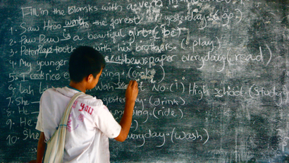 Boy at chalkboard writing in English (Thailand).