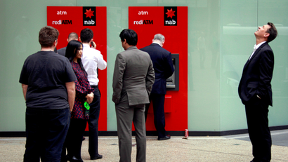 A man looks up as he stands next to a line for two National Australia Bank Ltd (NAB) automatic teller machines (ATMs) in central Sydney in this picture taken August 23, 2013.