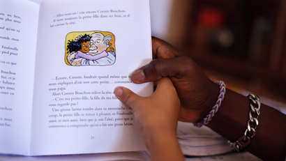 an adult and child look at a book in French