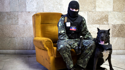 A masked pro-Russian protester sits beside a dog as he poses for a picture inside a regional government building in Donetsk, eastern Ukraine April 25, 2014. Picture taken April 25, 2014.