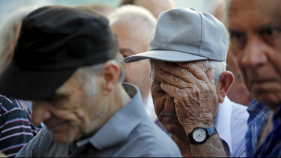 Pensioners wait in front of the main entrance of a National Bank branch to receive part of their pensions in central Athens.